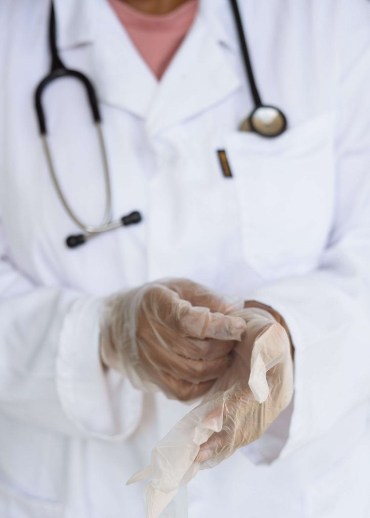 An orthopedic surgeon putting on disposable gloves and a stethoscope around their neck.