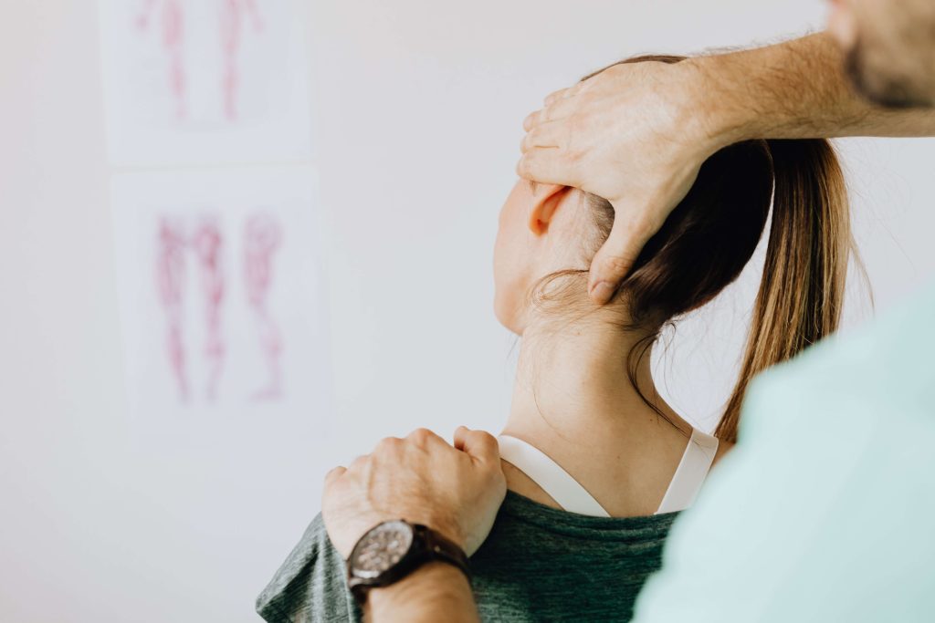 A doctor checking the mobility in the neck of a female patient.